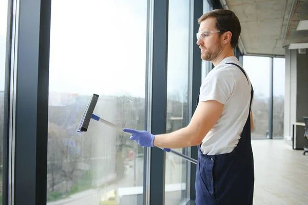Cleaner squeegeeing a large interior window pane